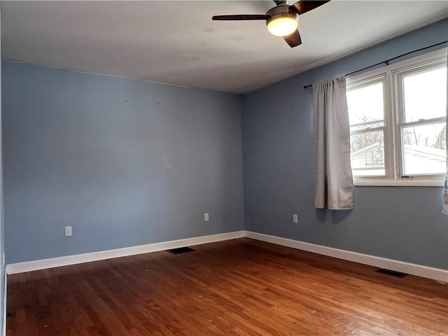 spare room featuring visible vents, ceiling fan, baseboards, and wood finished floors