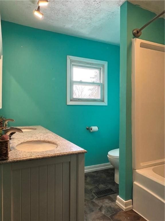 full bath featuring double vanity, toilet, a textured ceiling, shower / washtub combination, and a sink