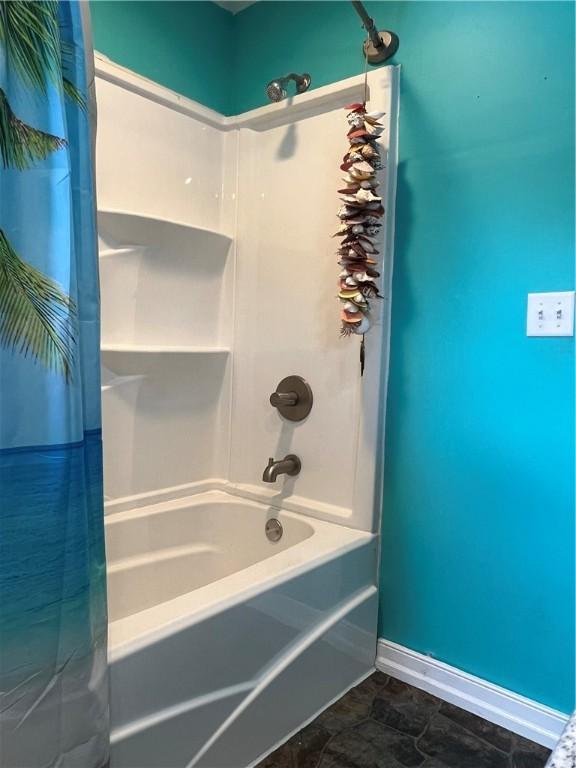 bathroom with baseboards and shower / tub combo with curtain