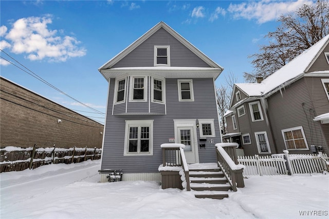 snow covered house featuring fence