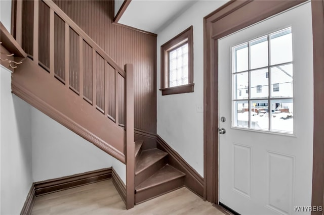 entryway featuring light wood-type flooring, plenty of natural light, stairs, and baseboards