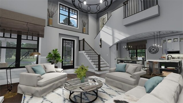 living area with a chandelier, wood finished floors, a high ceiling, and stairs