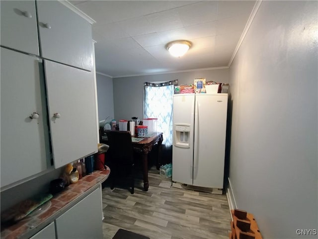 kitchen featuring ornamental molding, white refrigerator with ice dispenser, and light wood-style floors