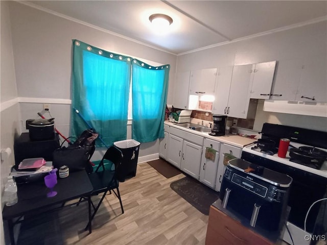 kitchen featuring light wood-style floors, light countertops, white cabinets, and ornamental molding