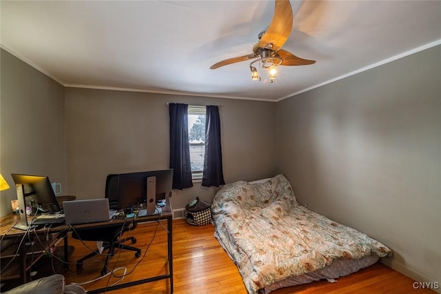 bedroom featuring baseboards, wood finished floors, and crown molding