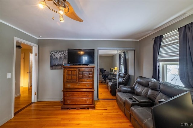 living room featuring light wood-style floors, baseboards, ornamental molding, and a ceiling fan