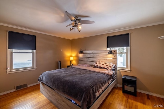 bedroom featuring baseboards, ornamental molding, visible vents, and light wood-style floors