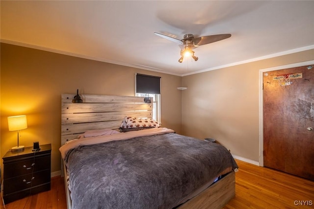 bedroom featuring ceiling fan, ornamental molding, wood finished floors, and baseboards