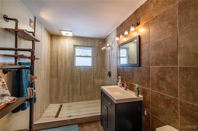 bathroom with tile walls, vanity, and a walk in shower