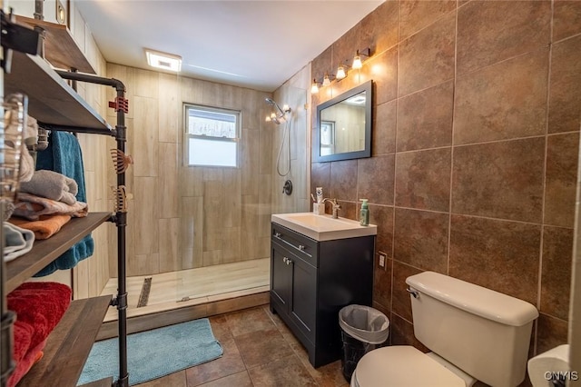 full bathroom featuring tile walls, toilet, vanity, tile patterned flooring, and tiled shower