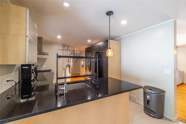 kitchen with recessed lighting, a peninsula, a sink, hanging light fixtures, and dark stone counters