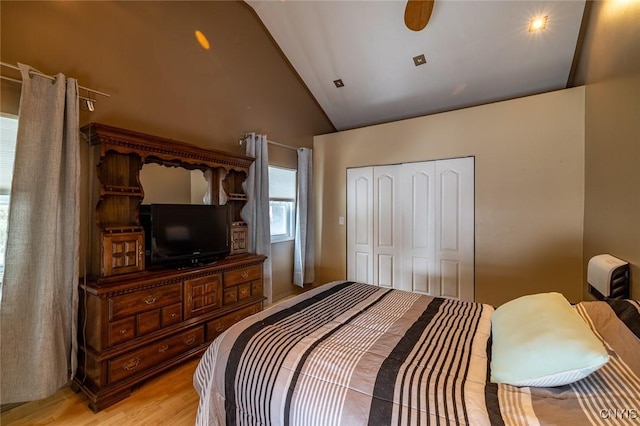 bedroom with lofted ceiling, light wood-style floors, ceiling fan, and a closet