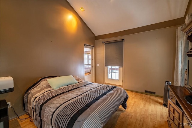 bedroom with light wood-style floors, baseboards, visible vents, and high vaulted ceiling