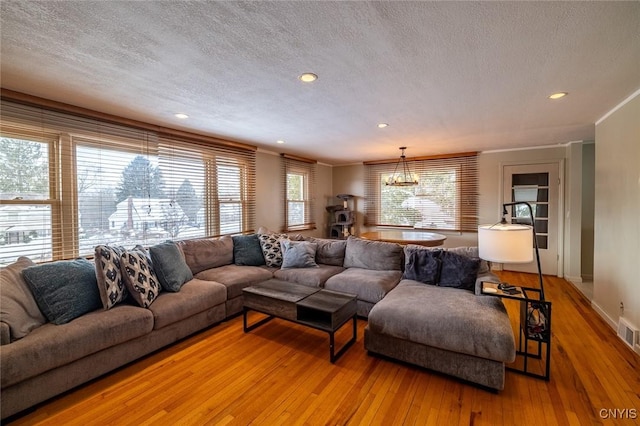 living room featuring a textured ceiling, light wood finished floors, recessed lighting, and an inviting chandelier