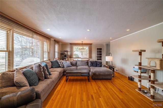 living room with a textured ceiling, light wood-style flooring, recessed lighting, baseboards, and ornamental molding