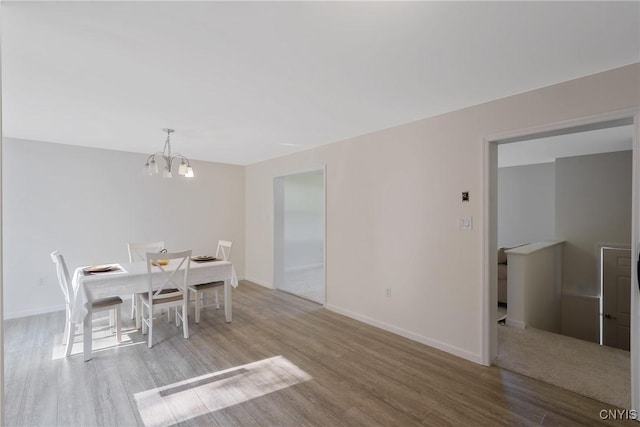 dining area with baseboards, wood finished floors, and a notable chandelier