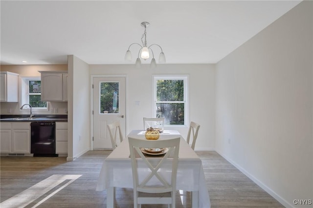 dining space with a chandelier, a wealth of natural light, light wood-style flooring, and baseboards