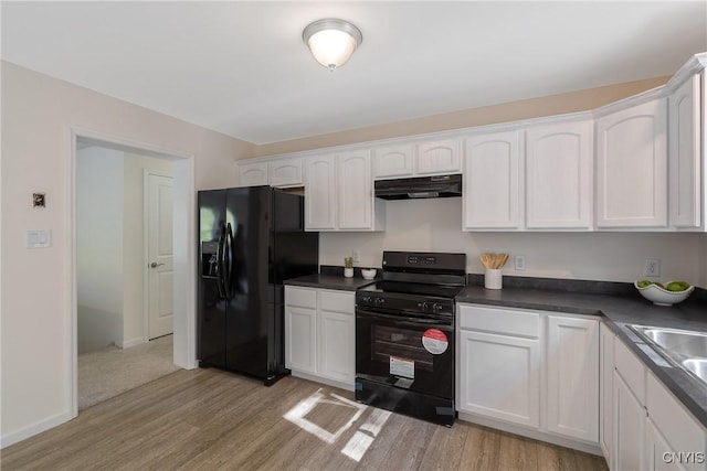 kitchen with dark countertops, white cabinets, light wood-type flooring, under cabinet range hood, and black appliances