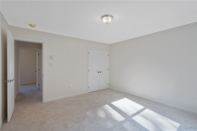 unfurnished bedroom featuring a closet, light colored carpet, and baseboards