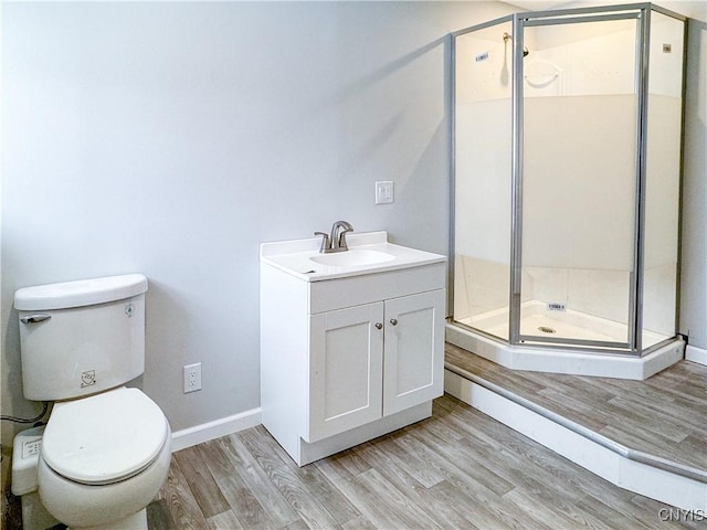 bathroom with toilet, a stall shower, wood finished floors, and vanity