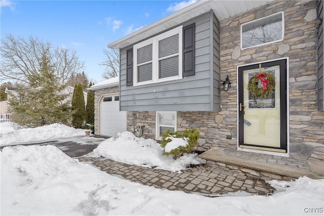 snow covered property entrance with stone siding