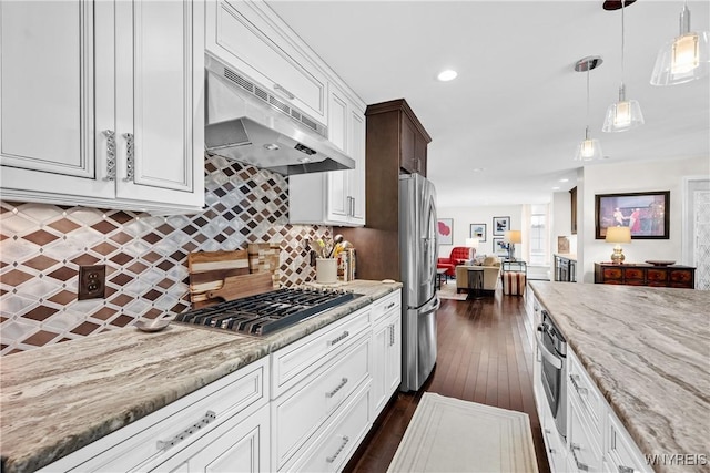 kitchen featuring light stone counters, decorative light fixtures, stainless steel appliances, under cabinet range hood, and backsplash