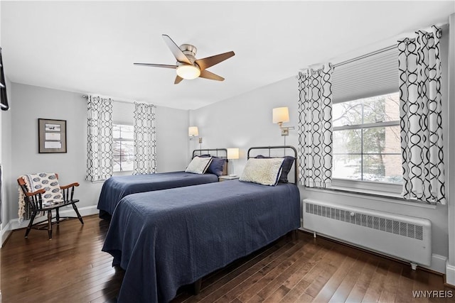 bedroom featuring dark wood-type flooring, multiple windows, and radiator heating unit