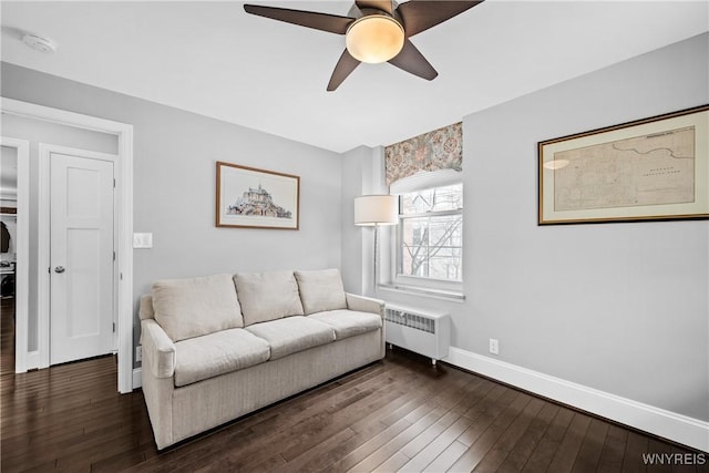 living area with radiator, a ceiling fan, baseboards, and dark wood-style flooring