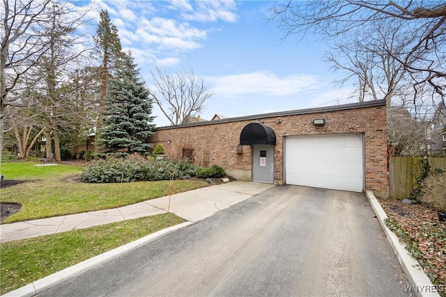 view of front of home featuring a garage, aphalt driveway, fence, a front lawn, and brick siding