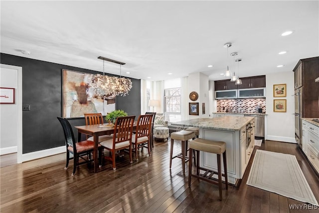 kitchen featuring dark wood-style floors, dark brown cabinets, a kitchen island, and pendant lighting