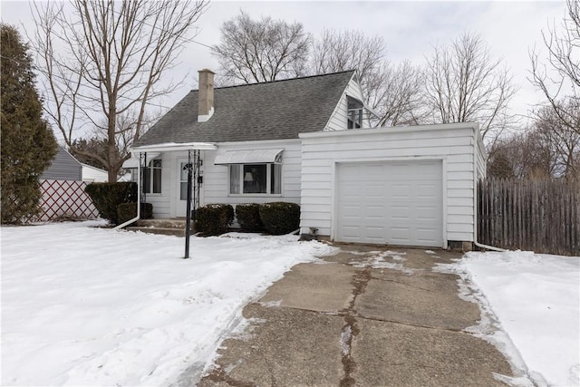 cape cod-style house featuring an attached garage, driveway, a chimney, and roof with shingles