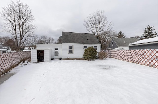 snow covered property with an outdoor structure and fence