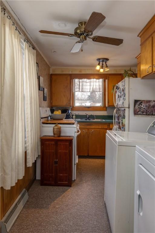 kitchen featuring white appliances, baseboard heating, washing machine and dryer, and brown cabinets