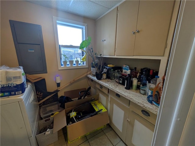 kitchen featuring light tile patterned floors, washer / clothes dryer, electric panel, and light stone countertops