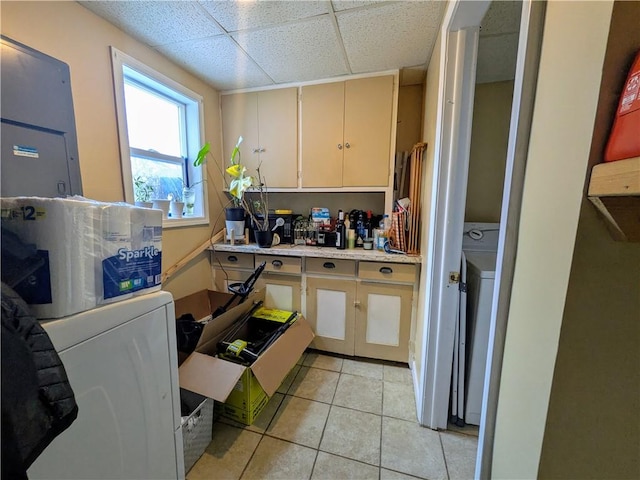 kitchen with light tile patterned floors, light countertops, a drop ceiling, and washer / dryer