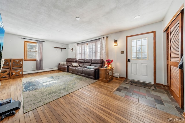 living area with a textured ceiling, a baseboard radiator, a baseboard heating unit, baseboards, and light wood-style floors