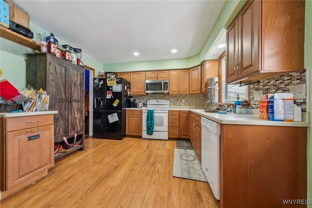 kitchen featuring white appliances, brown cabinetry, light wood-style flooring, light countertops, and a sink