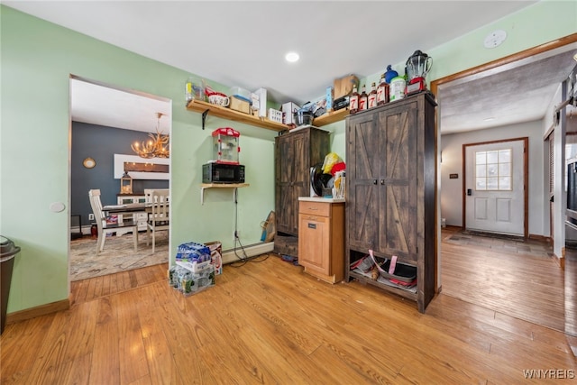 miscellaneous room featuring a baseboard radiator, light wood-style flooring, baseboards, and an inviting chandelier