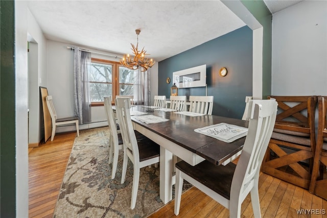 dining area with light wood-style flooring, a chandelier, and baseboard heating