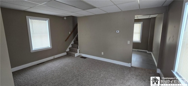 basement with stairway, a drop ceiling, carpet flooring, and baseboards