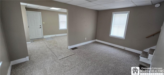 unfurnished room featuring visible vents, stairway, light carpet, a drop ceiling, and baseboards