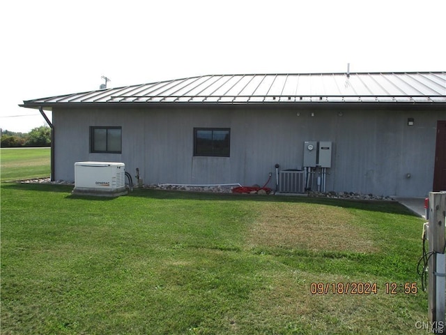 back of property with metal roof, a standing seam roof, and a lawn