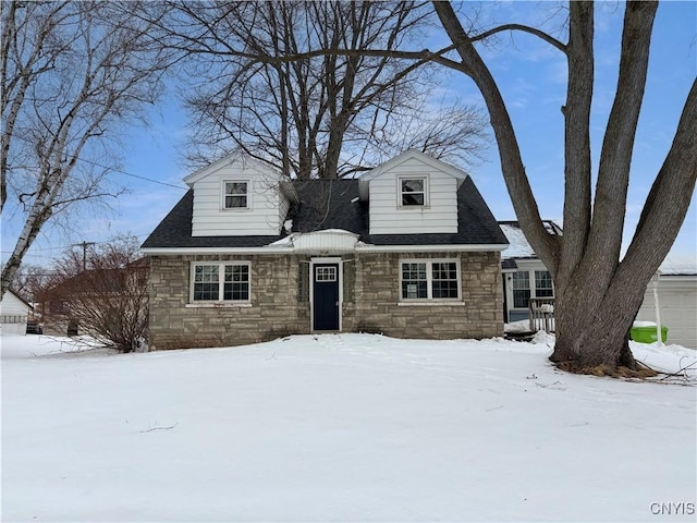 cape cod-style house featuring stone siding and roof with shingles