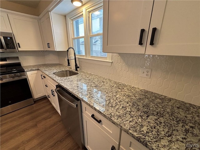 kitchen featuring light stone counters, appliances with stainless steel finishes, white cabinets, and a sink