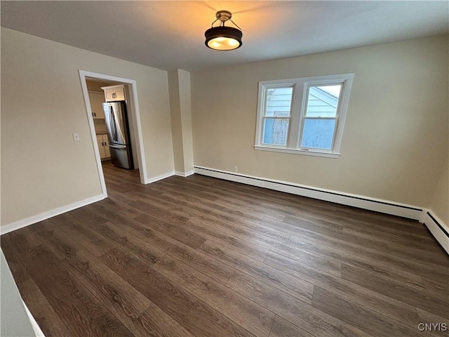 unfurnished room with dark wood-style floors, baseboard heating, and baseboards