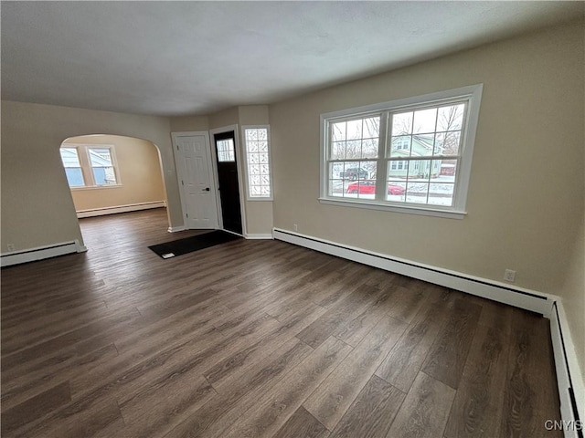 foyer entrance with a baseboard radiator, arched walkways, baseboard heating, and dark wood finished floors