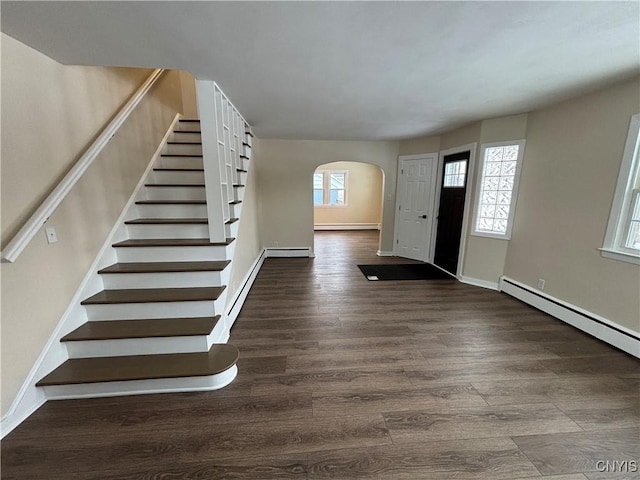 foyer with arched walkways, a baseboard radiator, stairway, dark wood-type flooring, and baseboards