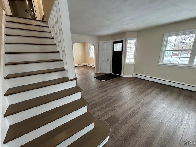 entryway with arched walkways, dark wood finished floors, a baseboard radiator, stairs, and a baseboard heating unit