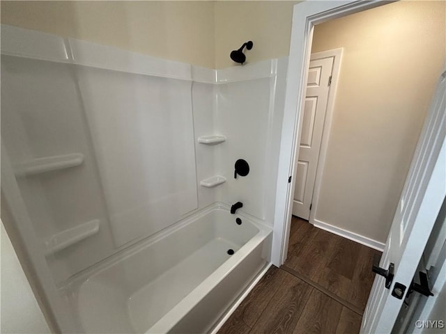 full bath with bathtub / shower combination, wood finished floors, and baseboards