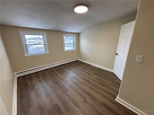 empty room with dark wood-style flooring, baseboard heating, and baseboards